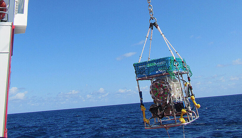 A measuring device is lowered from an research ship into the open ocean